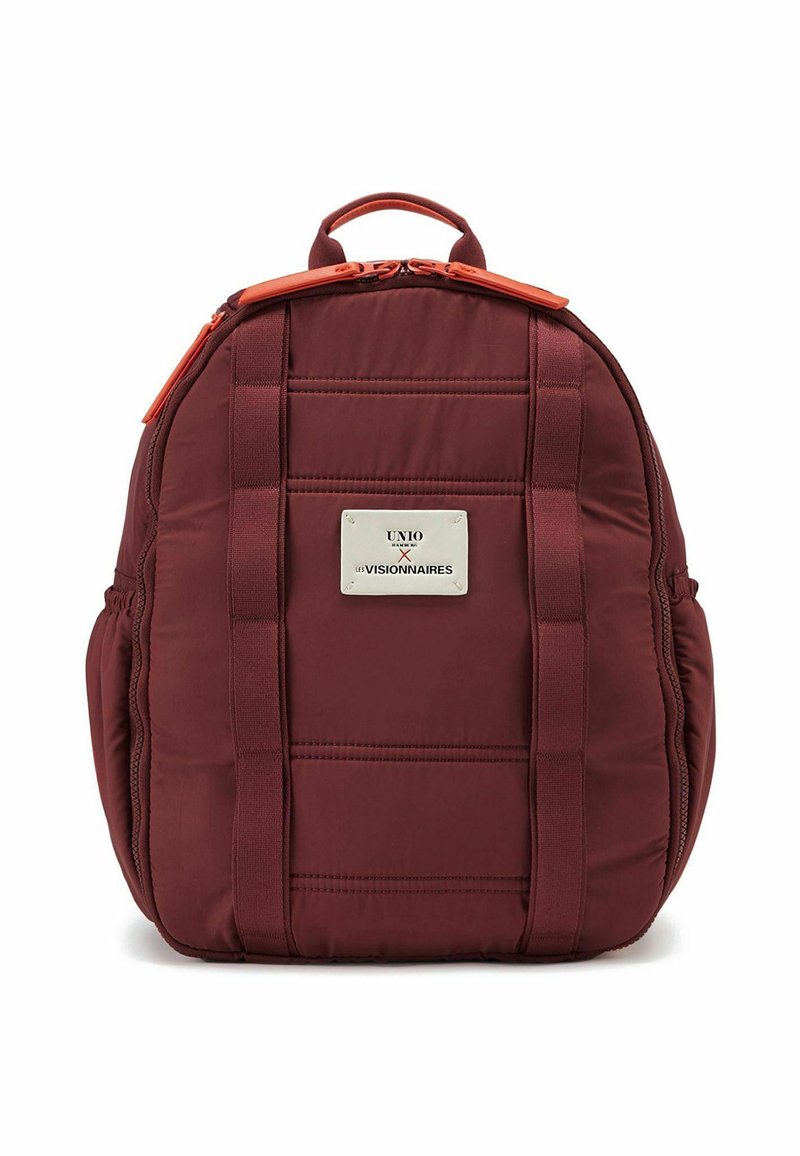 Mochila acolchada color burdeos con textura suave, detalles en cremallera naranja y una placa de logo plateada de marca. Cuenta con correas dobles para llevar.