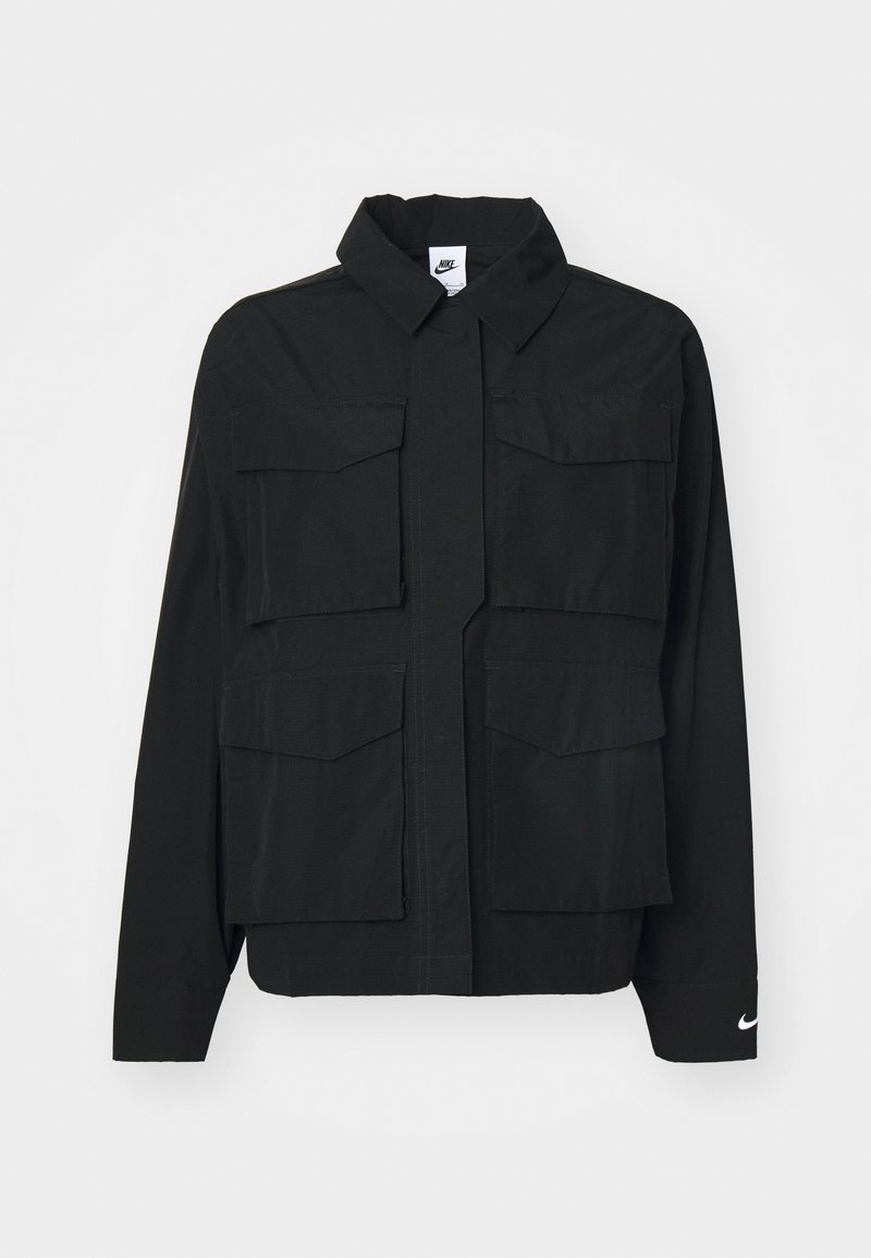 Veste noire avec un col, dotée de deux grandes poches avant et d'un logo Nike au poignet. Conçue en tissu lisse et léger.