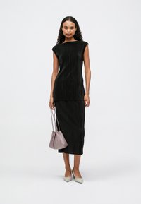 Μαύρο πλισέ φόρεμα με κοντά μανίκια, συνδυασμένο με μια ανοιχτό μωβ τσάντα και μπεζ γόβες με αιχμηρή μύτη. Λεπτό ύφασμα, μήκος midi.