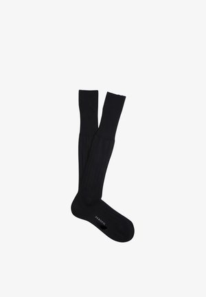 Calzini neri fino al ginocchio con texture a coste, uno sovrapposto all'altro, che mostra il nome del marchio "PEROFIL" sulla suola.