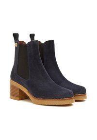 Botas de tobillo de ante azul marino oscuro con paneles laterales elásticos, tacón apilado y suela de goma. Presentan tiradores en la parte superior para facilitar su colocación.