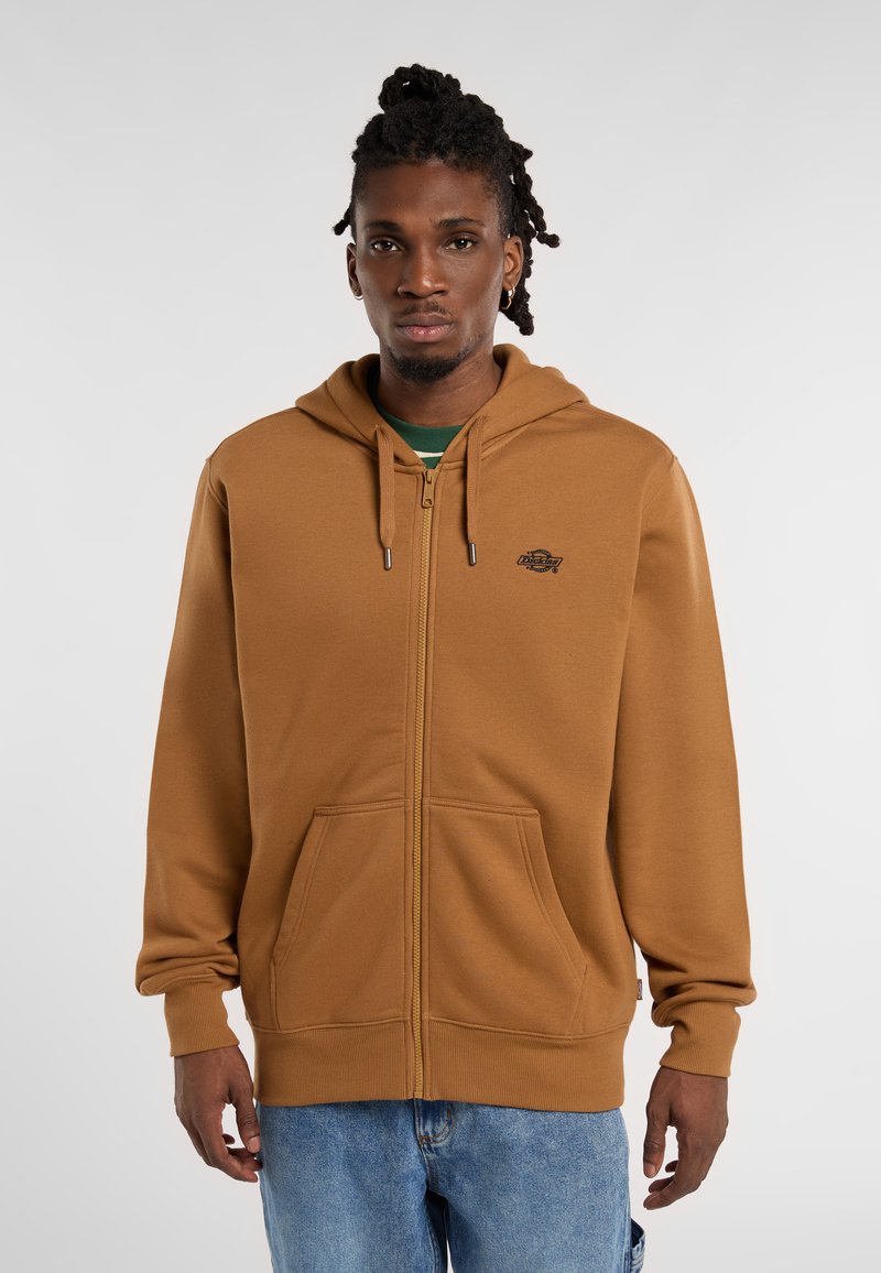 Brown zip-up hoodie made from soft fabric, featuring a kangaroo pocket, drawstring hood, and a small logo on the chest.