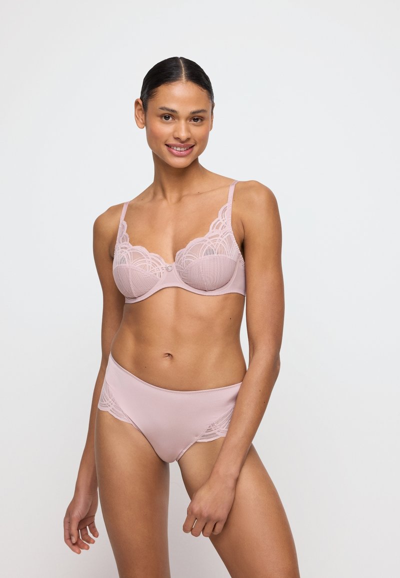 Jasnoróżowy komplet bielizny, składający się z koronkowego biustonosza z falbaniastymi brzegami i ozdobnymi detalami, w połączeniu z gładkimi pasującymi majtkami.