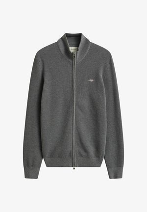 Grå strikket trøje med fuld lynlås, høj krave, lange ærmer, ribstrikkede manchetter og kant samt lille broderet logo på venstre bryst.