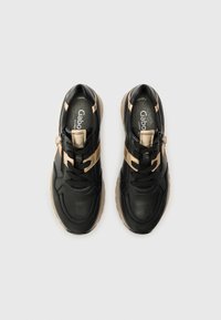 Svarte og gull sneakers med glatt lærøvre, teksturerte detaljer, snøring og en kraftig gummisåle.