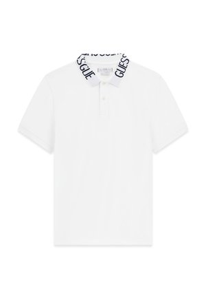 Witte polo met korte mouwen, drie knopen en een witte kraag met zwarte "GUESS" logo tekst rondom.