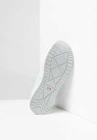 Sneaker bianco con suola testurizzata caratterizzata da un motivo geometrico, branding sottile e etichetta di dimensione 37, inclinato su uno sfondo bianco.