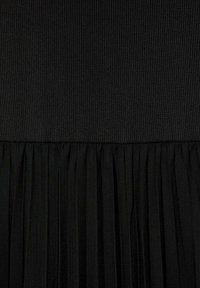 Schwarzes Kleid mit einem gerippten Oberteil und einem gefältelten Rock. Das Material wirkt glatt und strukturiert, was einen Lagen-Effekt erzeugt.