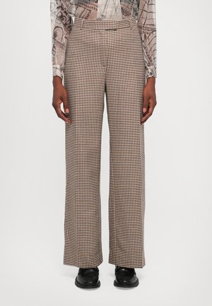 Pantaloni cu carouri maro și crem, cu un design larg. Dotati cu o talie ajustată și un material ușor texturat. Asortați cu pantofi negri.