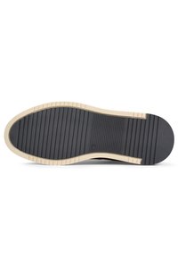 Suola di scarpa in gomma nera con un intersuola color crema. Presenta scanalature orizzontali per una maggiore trazione e bordi arrotondati per una finitura liscia.