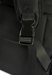 Szczegół czarnego plecaka z plastikowym zapięciem i teksturowanym paskiem, podkreślający gładki, trwały materiał. Dodatki obejmują plecione paski.