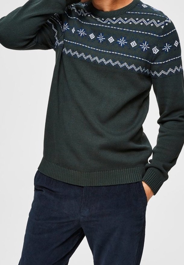 Mörkgrön stickad tröja med rund halsringning, prydd med vita och blå geometriska mönster över bröstet samt ribbade muddar och nederkant.