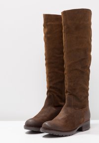 Bottes en suède marron jusqu'au genou avec un talon plat ; finition texturée et design épuré ; bout arrondi et semelle en caoutchouc robuste.