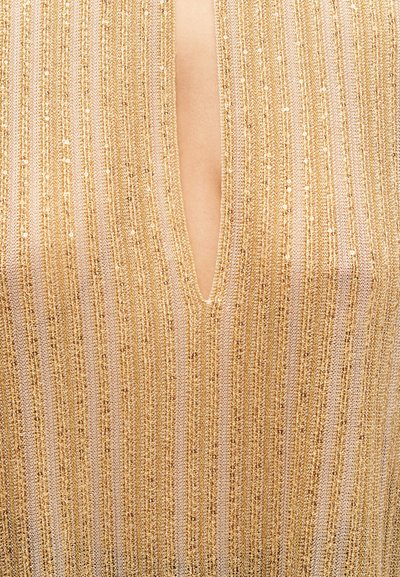 Πλεκτό ύφασμα με κάθετες ρίγες σε χρυσό και μπεζ χρώμα με λεπτές μεταλλικές κλωστές και βαθιά λαιμόκοψη V που αποκαλύπτει το δέρμα από κάτω.