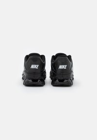 Zapatillas Nike negras con una parte superior de malla texturizada, cuello acolchado y suela de goma con cápsulas de amortiguación de aire visibles en el talón.