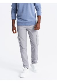 Lichtgrijze cargobroek met twee zijzakken. Gemaakt van duurzaam materiaal, met een tapered fit en gestikte details. Gedragen met witte sneakers.