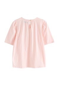 Kurzärmliges, rundhalsiges rosa Oberteil aus weicher Baumwolle. Mit gerafften Schultern, Spitzenbesatz und einer kleinen Öffnung mit Schlüsselloch im Rücken.