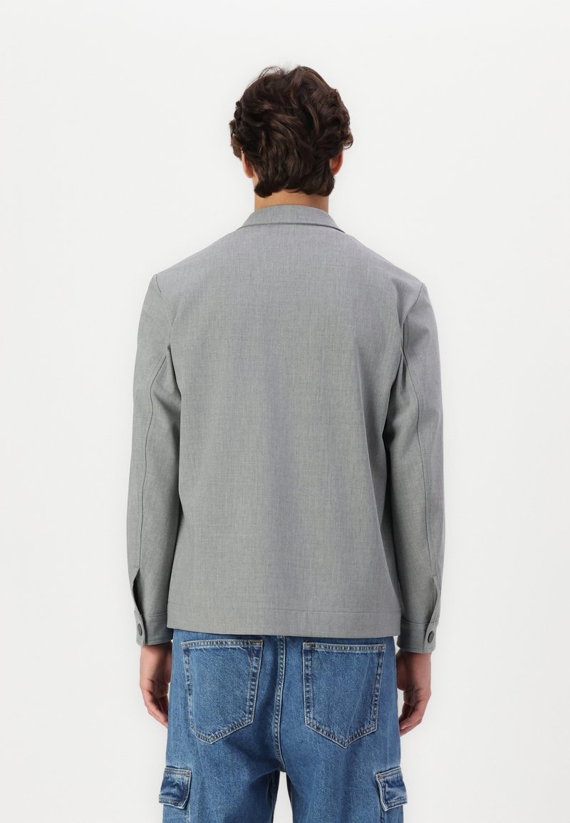 Szara, casualowa kurtka o miękkiej strukturze, dopasowanym kroju i zapięciu na jeden guzik. Posiada długie rękawy i wysoki kołnierz.