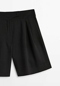 Pantaloni corti neri con un design anteriore plissettato, realizzati in un tessuto leggero. Presentano una chiusura con bottone in vita e tasche laterali.