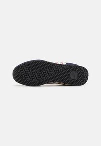 Black rubber outsole with circular tread patterns; features a flexible design and varying textures for grip and traction.