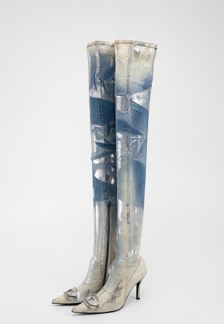 Stivali al ginocchio realizzati con un mix di denim blu e materiali argentati lucidi, punta affusolata, tacco basso e accenti decorativi sulla punta.
