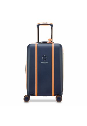 Valigia rigida blu navy con cinturini in pelle color cuoio, quattro ruote e manico estensibile, marchiata "Roland Garros Paris."