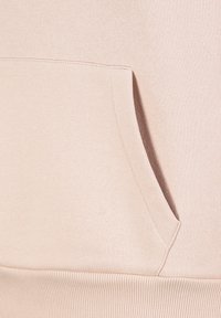 Hellrosa Sweatshirt mit Kängurutasche, geripptem Saum und weicher Textur. Der Stoff hat eine glatte Oberfläche mit dezenten Nähten.