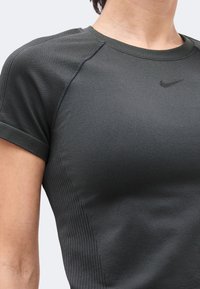 Κοντινό πλάνο ενός ατόμου που φοράει σπορ μαύρο γκρι κοντομάνικο Nike με πλευρικές ριμπ λεπτομέρειες και στρογγυλή λαιμόκοψη.