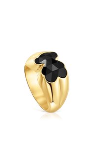 Anello d'oro con una fascia larga che presenta una pietra nera sfaccettata a forma di orsetto stilizzato sulla parte superiore.