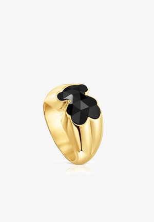 Anello d'oro con una fascia larga che presenta una pietra nera sfaccettata a forma di orsetto stilizzato sulla parte superiore.