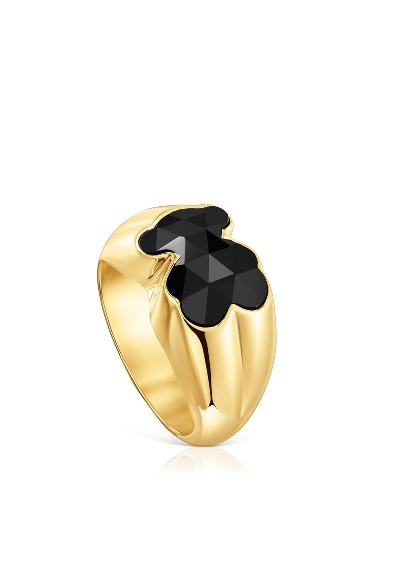 Anello d'oro con una fascia larga che presenta una pietra nera sfaccettata a forma di orsetto stilizzato sulla parte superiore.