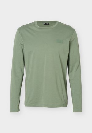 Svetlozelené tričko s dlhými rukávmi a okrúhlym výstrihom, s jemným logom na hrudi a rovnými lemami, zobrazené na jednoduchom svetlosivom pozadí.