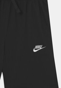 Černé sportovní šortky z měkké tkaniny, s elastickým pasem, šňůrkou a bílým vyšívaným logem Nike na přední straně.