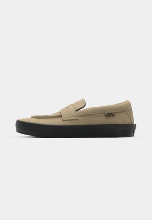 Beige instap schoen met een zachte stoffen bovenkant, zwarte rubberen zool en een enkele strap-sluiting. Kenmerkt zich door minimale stiksels en een logo-accent.
