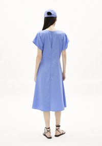 Vestido de poliéster azul con mangas cortas con volantes, cintura ajustada y dobladillo a la altura de las rodillas. Dispone de un cierre en la parte trasera y detalles de costura mínimos.