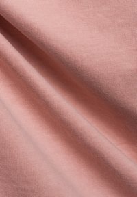 Weiches rosa Baumwollgewebe mit glatter Textur und feiner Rippung, das Falten und Knicke zeigt, um Tiefe und Dimension zu verleihen.