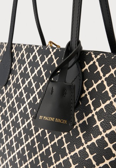 Sac à main texturé noir et blanc avec un motif en forme de diamant, anses en cuir noir et une petite étiquette noire embossée "BY MALENE BIRGER" en or.