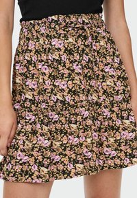 Gonna nera a fiori con vita arricciata, con fiori rosa e gialli su uno sfondo nero, realizzata in tessuto leggero.