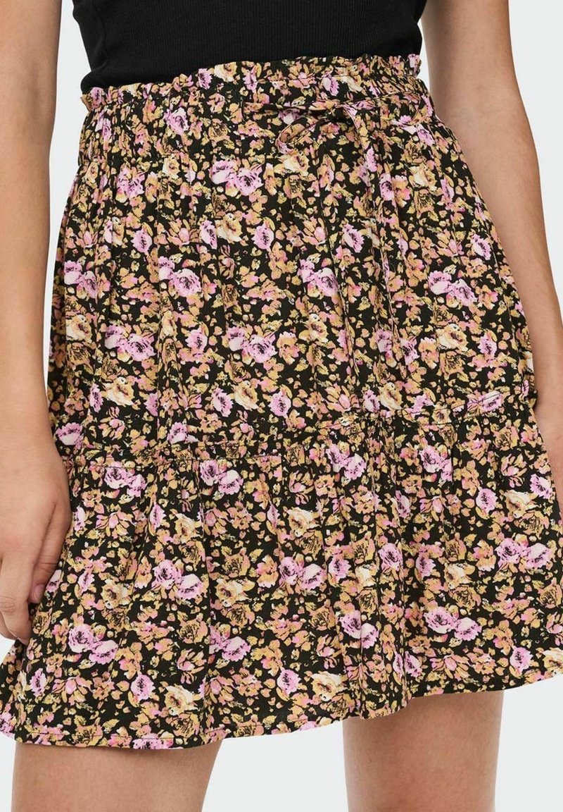 Gonna nera a fiori con vita arricciata, con fiori rosa e gialli su uno sfondo nero, realizzata in tessuto leggero.