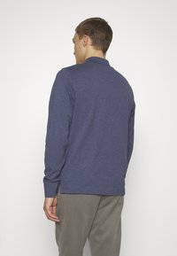 Marineblaues Langarm-Polohemd aus weichem Stoff, mit klassischem Kragen, seitlichen Schlitzen und einer leicht lässigen Passform.