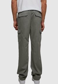 Spodnie cargo w stonowanym szarym materiale, z bocznymi kieszeniami, luźnym krojem oraz tylnymi kieszeniami z patkami. Minimalistyczny design z przeszyciami.