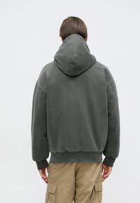 Φούτερ με κουκούλα σε σκούρο γκρι ύφασμα, με άνετη εφαρμογή, ριβέ μανσέτες και στρίφωμα, με απαλή υφή και χωρίς ορατά σχέδια.