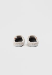 Beige comfortabele slippers gemaakt van zachte, gestructureerde stof met een fuzzy buitenkant en een gladde binnenkant. Ronde vorm, platte zolen.