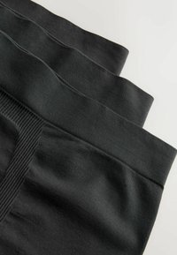 Must väike must puuvillane bokserite paar, millel on lai ribaga vöökoht, sujuva tekstuuriga ja mugavalt istuv, on laotud virna.