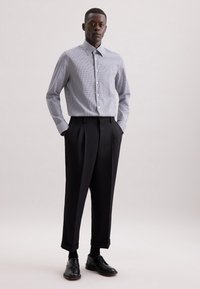 Gingham-gepatroniseerde button-up shirt in wit en marineblauw; hoge taille zwarte geplooide broek; zwarte veterschoenen; slim fit.