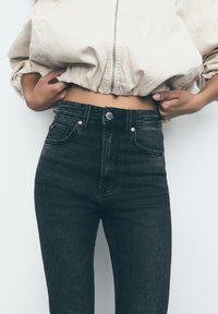 Hoge zwarte denim jeans met een lichte stretch, voorzien van koperen klinknagels, een knoopsluiting en een klassiek vijf-pocketdesign.