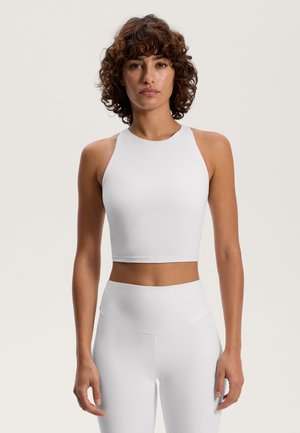 White cropped tank top with a high neck and sleeveless design, made from a smooth, stretchy material, paired with matching high-waisted leggings.