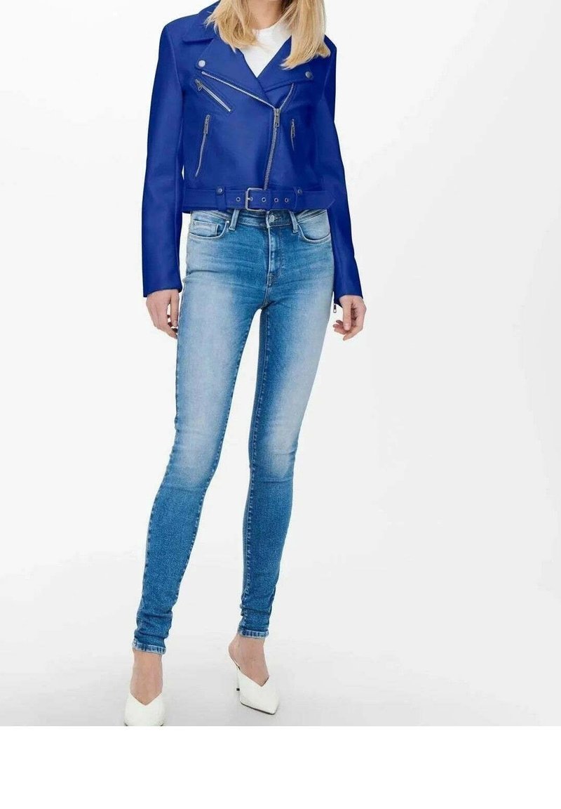 Blå faux läder kort motorcykeljacka med två dragkedjefickor, kombinerad med ljusblå snäva jeans och vita klackskor.