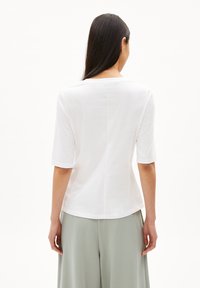 Witte katoenen T-shirt met driekwartmouwen, ronde hals en een licht gebogen zoom. Glad textuur en minimalistisch ontwerp.