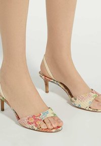 Bloemenprint open teen slingback hakken met een beige band. Heeft een slanke hak en een textuur stof met meerkleurige bloemenaccenten.
